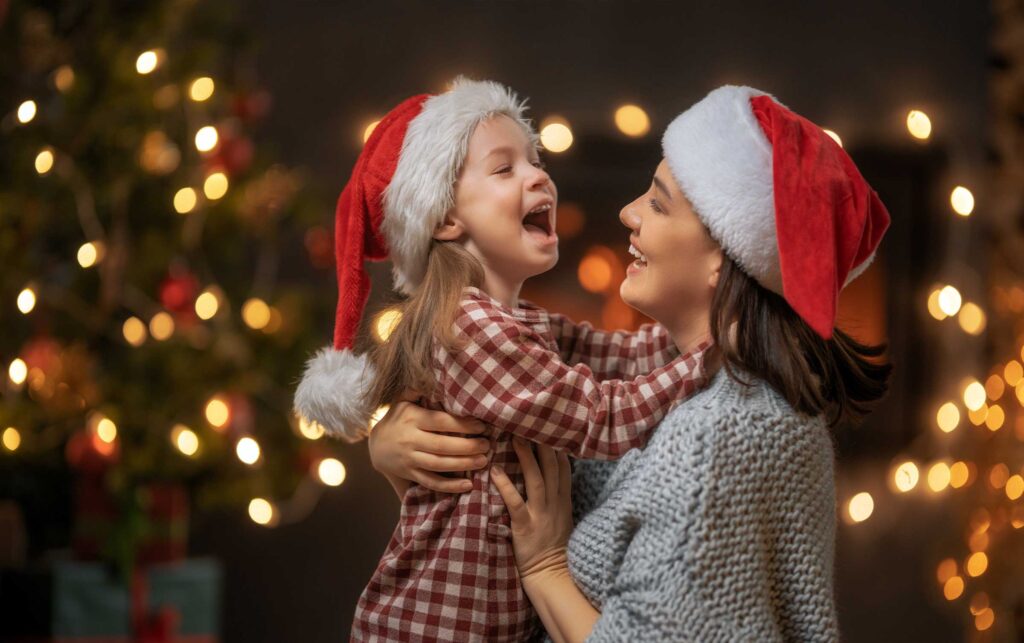 Mãe e filha compartilhando o espírito natalino enquanto trocam presentes debaixo da linda árvore de Natal. O amor e a alegria da época de Natal são evidentes na expressão das duas. Que este Natal traga muita felicidade e amor para sua família também